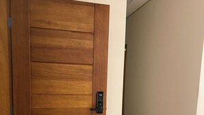 A wooden door with a modern handle, a hallway with white walls, and a tiled floor. - Lilly Queen I, 3-bedroom house in adorable Londrina with AC near to the Airport (Londrina)