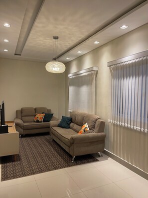 A modern living room with a sectional sofa, a patterned rug, and a pendant light.