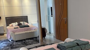 A modern bedroom with a bed, a bedside table, a mirror, and a wardrobe. - Lilly Queen I, 3-bedroom house in adorable Londrina with AC near to the Airport (Londrina)
