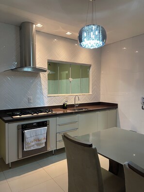 A modern kitchen with a gas stove, stainless steel range hood, and a glass island with a sink.