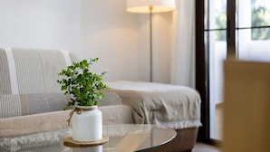 A living room with a sofa, a glass coffee table, a potted plant, and a floor lamp. - Barrosa Beach Apartment -Chiclana de la Frontera (Chiclana de la Frontera)