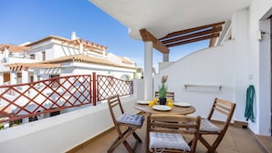A balcony with a table and chairs, a potted plant, and a view of buildings. - Barrosa Beach Apartment -Chiclana de la Frontera (Chiclana de la Frontera)