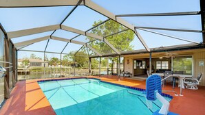Ein überdachter Pool mit Sprungbrett, Sonnenschirm und einer Terrassenfläche mit Sitzgelegenheiten.
