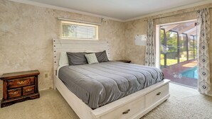 Ein Schlafzimmer mit Bett, Nachttisch, Fenster und Blick ins Freie.