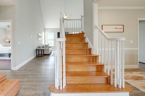 Eine Treppe mit weißen Geländern und Holzstufen, die zu einer zweiten Etage führt.