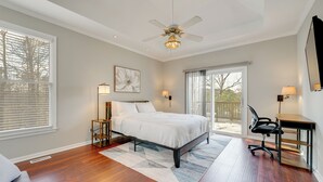 A bedroom with a bed, a desk, a chair, a ceiling fan, and a large window. - Private Yard & Pool Access! Family Home in Acworth (Acworth)