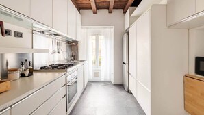 Una cocina moderna con armarios blancos, electrodomésticos de acero inoxidable y techo de madera.