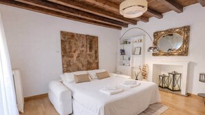 Un dormitorio con una cama grande, una chimenea, una estantería y un espejo.