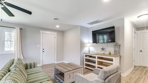 Una sala de estar con sofá, sillón, mesa de centro, televisor y estantería.
