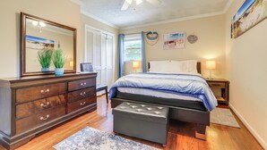 Ein Schlafzimmer mit Bett, Kommode, Spiegel, Deckenventilator und Wandbildern.