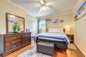 Ein Schlafzimmer mit Bett, Kommode, Spiegel, Deckenventilator und Wandbildern.