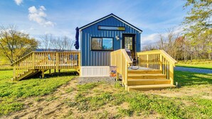 Uma pequena cabana azul com um deck de madeira e escadas que levam à entrada.