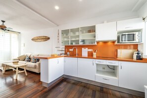 A modern kitchen with white cabinets, a wooden countertop, and a microwave. - Atlantic View Apartment - El Rompido (El Rompido)