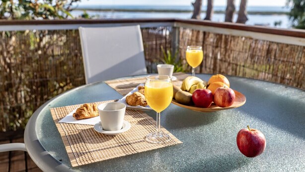 A breakfast setup on a balcony with a view of the sea, including croissants, fruit, and orange juice. - Atlantic View Apartment - El Rompido (El Rompido)