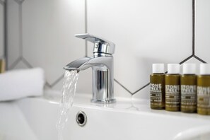 Ein Badezimmer mit einem modernen Wasserhahn, einem Waschbecken und einer Reihe von Pflegeprodukten.