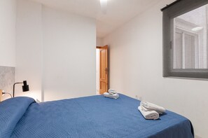 A bedroom with a bed, a window, a door, and a wall-mounted lamp. - Arenal Beach Escape - Burriana Port (Burriana)