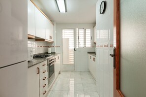 Cozinha com armários brancos, fogão e geladeira.