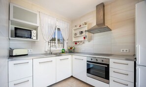 Eine moderne Küche mit weißen Schränken, einer Mikrowelle, einem Toaster, einem Herd und einem Spülbecken.