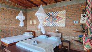 A room with two beds, a brick wall, a wooden ceiling, and a colorful geometric wall art piece.