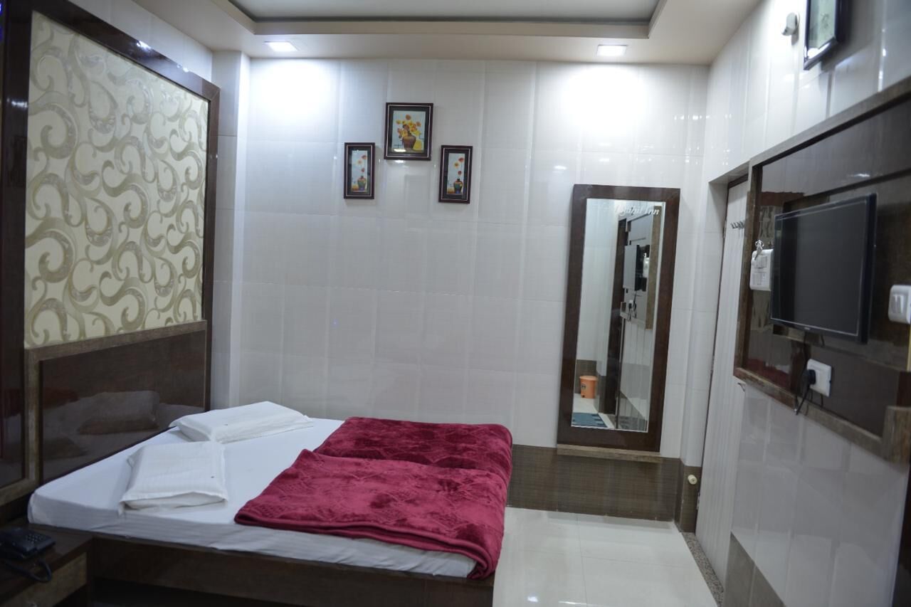 Habitación de hotel con cama, televisión, espejo y baño pequeño.