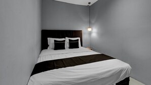 Una habitación de hotel moderna con una cama grande, un cabecero y una lámpara de noche.