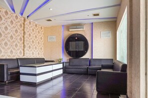 Un espace d’accueil comprenant un canapé, un comptoir de réception et un téléviseur fixé au mur.