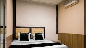 Hotellihuone, jossa on sänky, yöpöytä, ilmastointilaite ja seinä, jossa on geometrinen kuvio.
