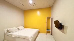 A bedroom with a bed, a yellow wall, a door, and a mirror on the wall.
