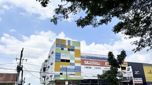 Un edificio de varios pisos con una fachada colorida, un cartel que indica 'ÁNCBA DAM' y diversos comercios.