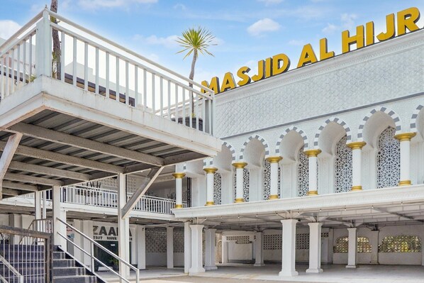 A multi-level building with a prominent sign reading 'MASJID AL HIJR' and a staircase leading to an upper level.