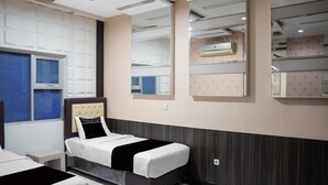 Ett hotellrum med en säng, ett fönster, en väggmonterad luftkonditioneringsanläggning och en spegel som reflekterar rummet.