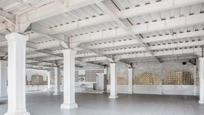 Un intérieur caractérisé par des colonnes blanches, un sol carrelé et des motifs décoratifs sur les murs.