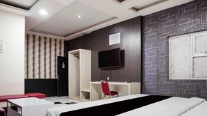 Une chambre d’hôtel avec un lit, un bureau, une télévision et un mur décoré de motifs.