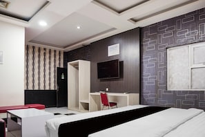Une chambre d’hôtel avec un lit, un bureau, une télévision et un mur décoré de motifs.