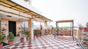 Un espace extérieur à carreaux, agrémenté de plantes en pot, d’une balançoire et offrant une vue sur le paysage urbain.