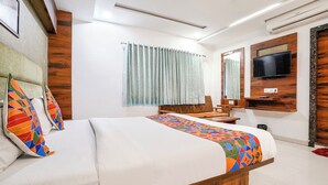 Une chambre d’hôtel équipée d’un lit, d’un bureau, d’une chaise, d’une télévision et d’une fenêtre avec des rideaux.