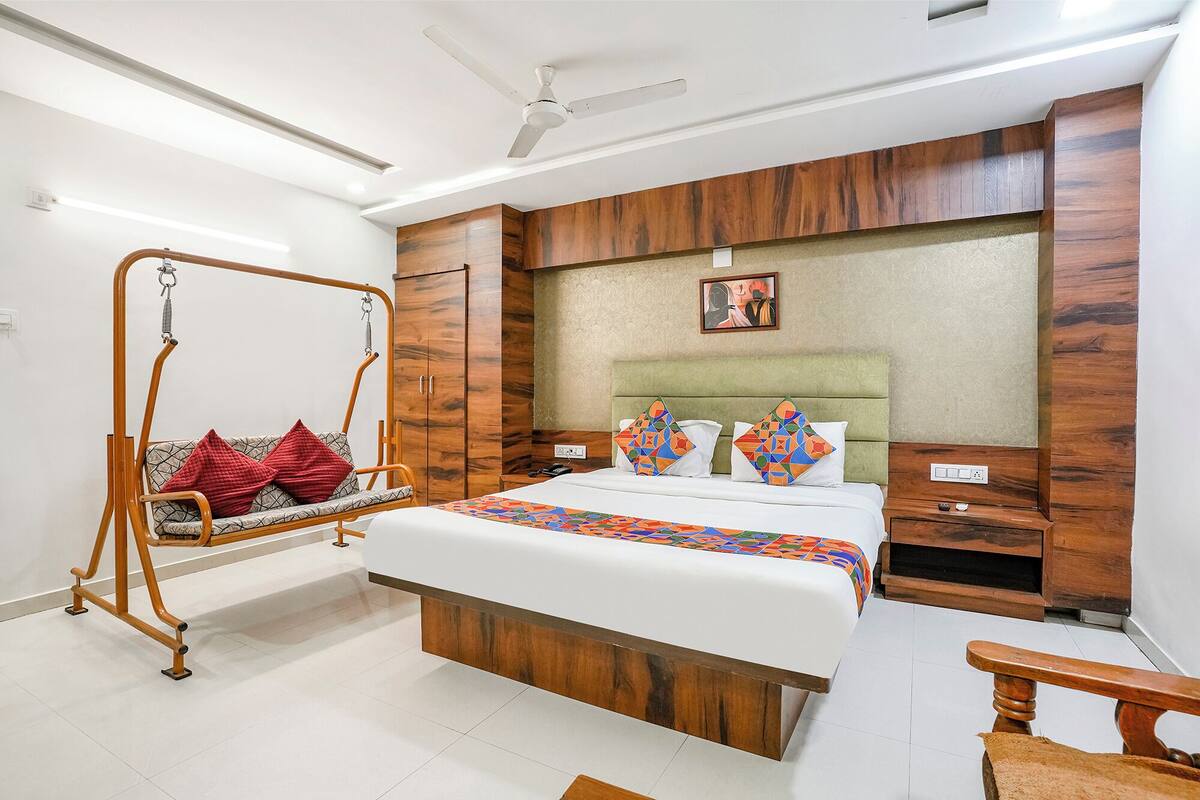 A bedroom with a bed, a hanging chair, a wardrobe, and a ceiling fan.