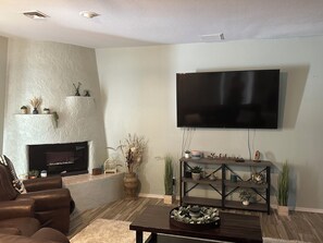 Ein Wohnzimmer mit Kamin, Flachbildfernseher, einer Couch und einem Couchtisch.