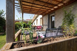 A covered patio with a wooden pergola, outdoor furniture, and a garden bed. - Holiday Home 'La Maison Et L'étang De Pêche' with Mountain View, Private Terrace and Wi-Fi (Vagney)