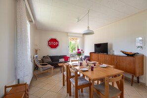 A dining area with a wooden table and chairs, a stop sign on the wall, a television, and a cabinet. - Holiday Home 'La Maison Et L'étang De Pêche' with Mountain View, Private Terrace and Wi-Fi (Vagney)