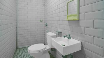 Un baño pequeño con paredes de azulejos blancos, un inodoro blanco, un espejo con marco verde y un lavamanos blanco.