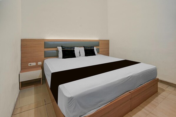 A neatly made bed with a wooden headboard and a bedside table with a drawer.