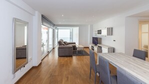 Ein modernes Wohnzimmer mit einer Couch, einem Esstisch und einem Fernseher.
