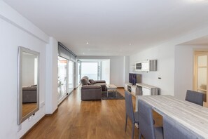 Ein modernes Wohnzimmer mit einer Couch, einem Esstisch und einem Fernseher.