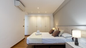 Ein Schlafzimmer mit Bett, Nachttisch, Lampe und Kleiderschrank.