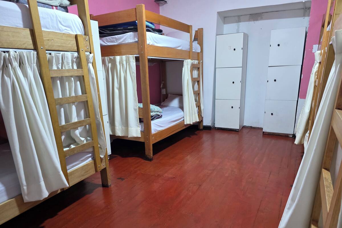 Habitación tipo dormitorio con literas, un armario y una escalera de madera.
