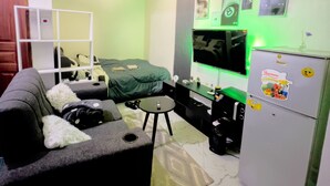 Un espacio habitable compacto con un sofá, una mesita, un televisor y un refrigerador.
