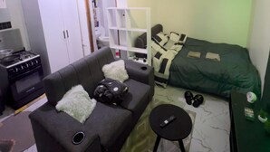 Habitación compacta con sofá, una mesita, cama, armario y ventilador de techo.