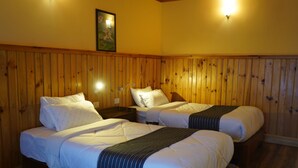 A room with two beds, wooden paneling on the walls, and a painting above the beds. - Tendrel Resort (Trongsa)
