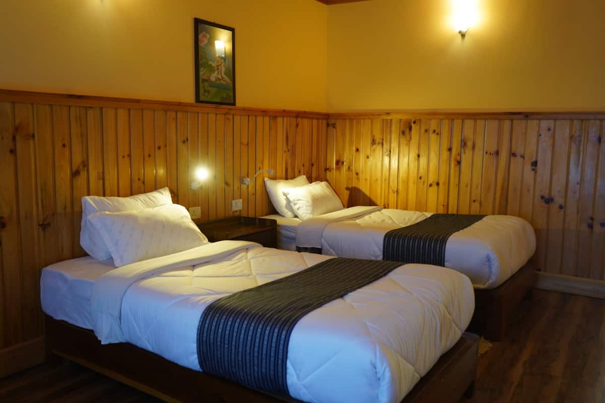 Una habitación con dos camas, paneles de madera en las paredes y un cuadro sobre ellas.